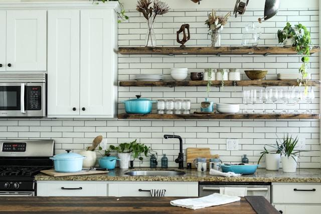 A modern kitchen area with stainless steel appliances, white cabinetry, and a marble countertop